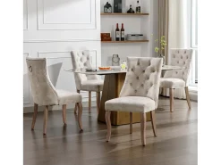 Conjunto de 4 sillas de terciopelo beige claro con patas de madera curvadas y botones decorativos.