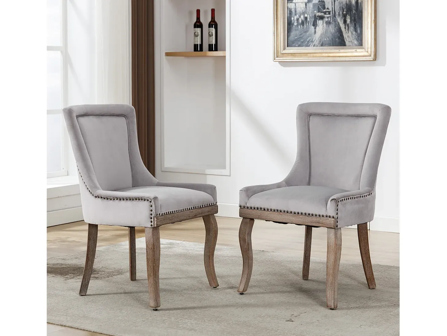 Juego de 2 sillas de terciopelo gris con patas de madera curvadas y remaches dorados.