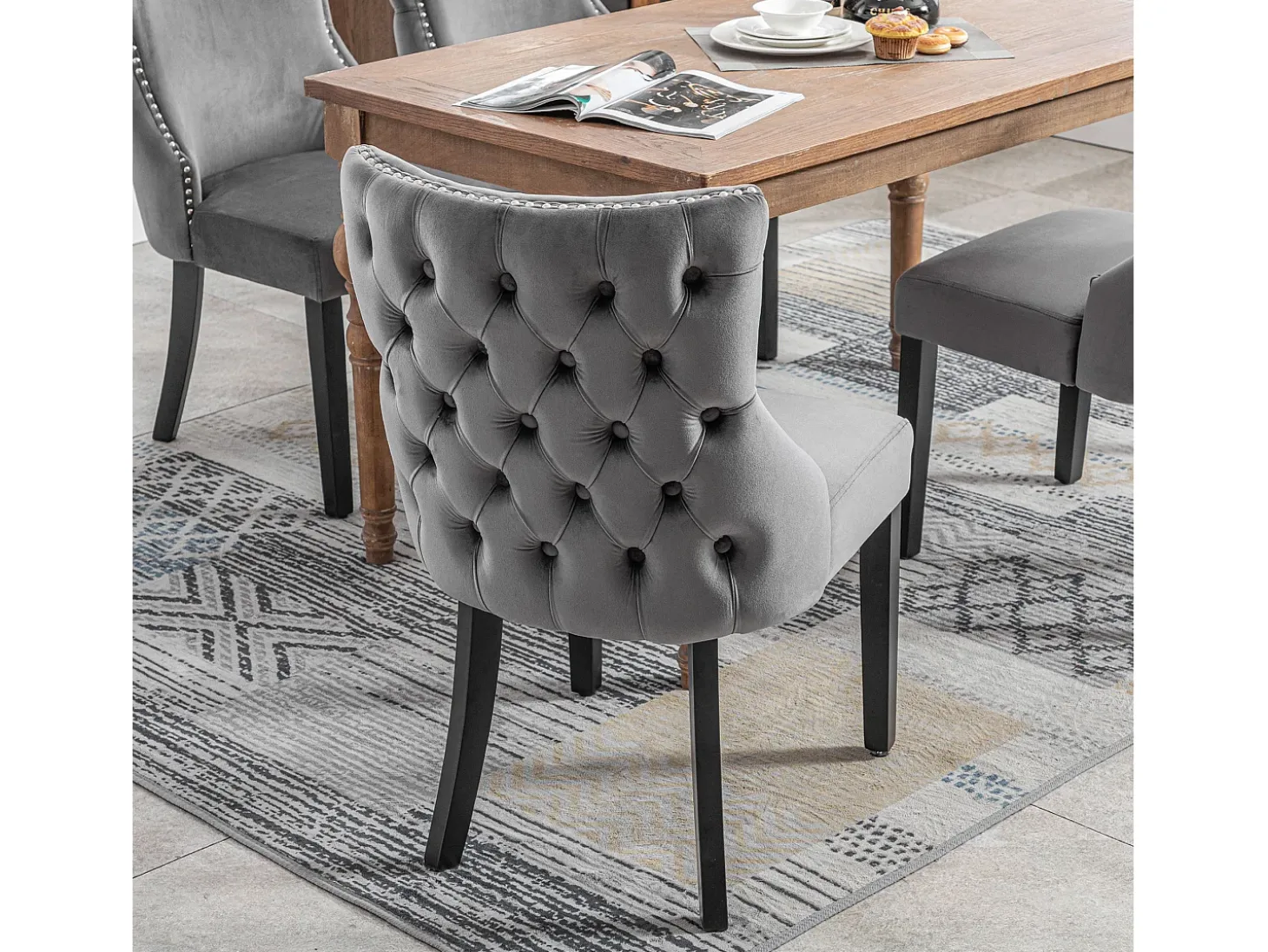Juego de 4 sillas de terciopelo gris con patas de madera gris, botones decorativos y remaches plateados.
